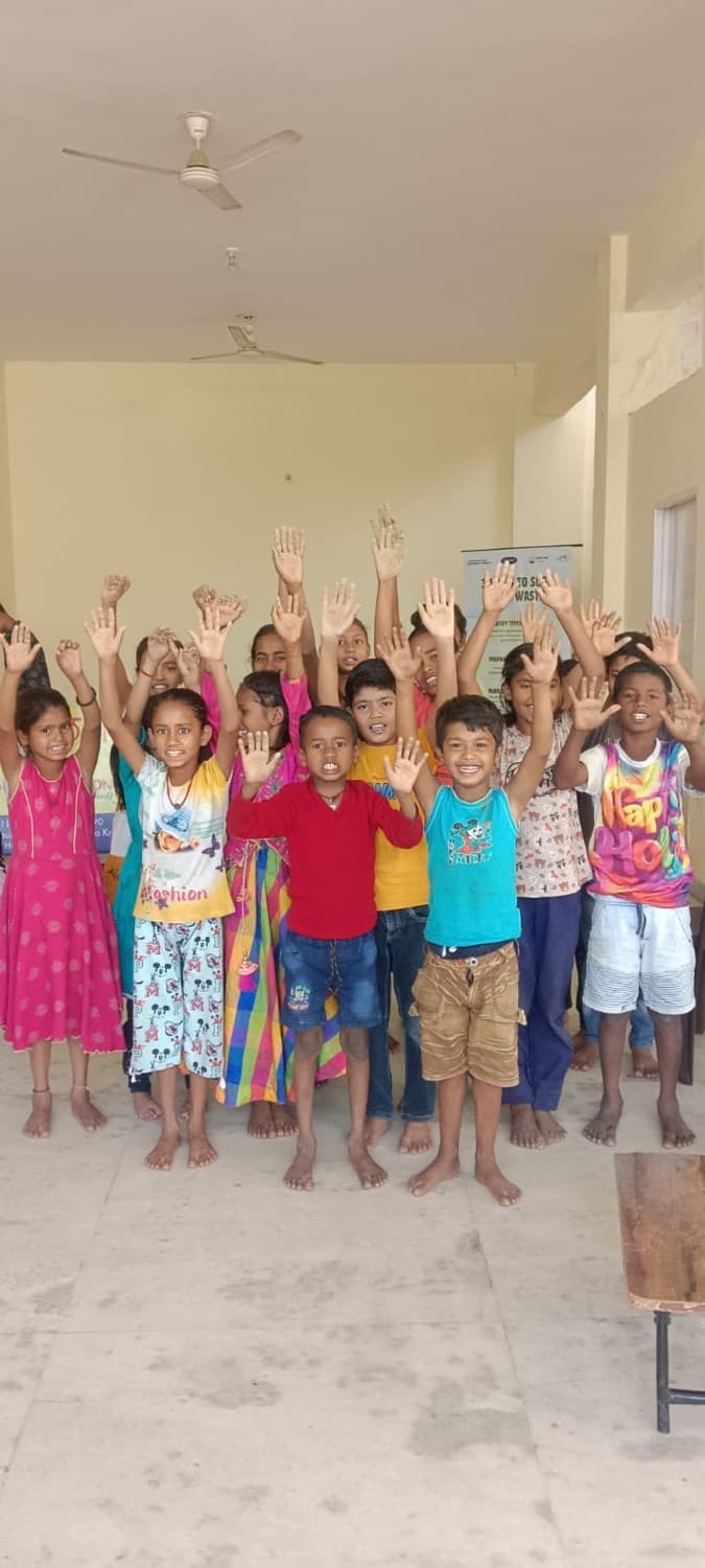 Children at Udaan Ki Paathshala raising their hands together, joyful classroom moment