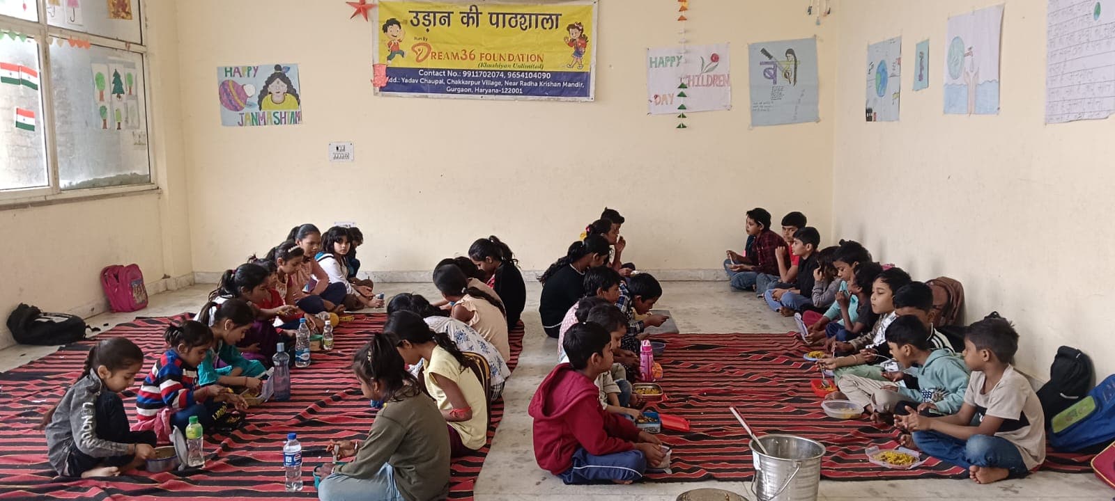 Children sharing a meal in two rows at the Udaan Ki Paathshala kitchen